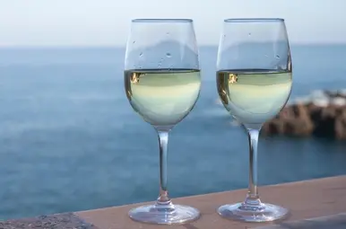 Twee wijnglazen met de oceaan op de achtergrond.