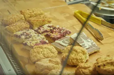 Een rij met verschillende scones op de toonbank van een bakkerij.