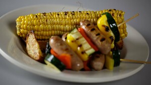 Maïskolf van de grill met worstspiesjes