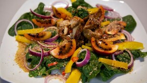 Maaltijdsalade met gekaramelliseerde kip, cassavemeel en wilde spinazie