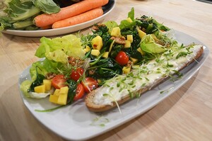Maaltijdsalade met spinazie, mango en balsamico azijn en een geitenkaasbroodje