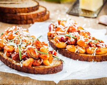 Toast met gebakken bonen in tomatensaus, rozemarijn en parmezaan