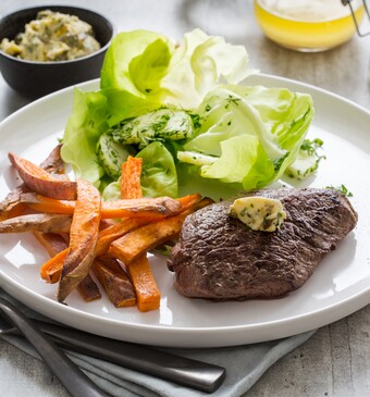 Steak frites met simpele beurre Café de Paris, zoete-aardappelfrietjes en tuinkruidensalade