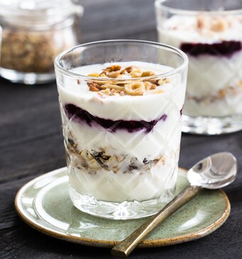 Feestelijke ontbijttrifle met laagjes jam, knapperige noten, voedzame muesli en yoghurt (of kwark). 