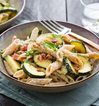 Magere penne carbonara met yoghurt, spekjes, courgette, Parmezaan en citroenrasp