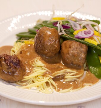 Balletjes in honingpindasaus met peultjessalade