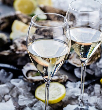 Twee wijnglazen met oesters op de achtergrond