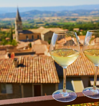 Twee wijnglazen met de Provence op de achtergrond.