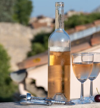 Twee glazen wijn met een fles en kersen.