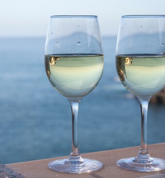 Twee wijnglazen met de oceaan op de achtergrond.