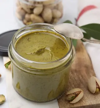 Pistachecrème in een potje met pistachenootjes eromheen.