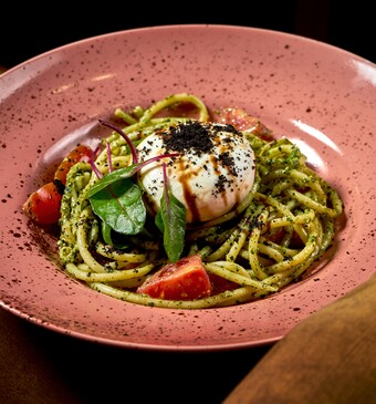 pasta pesto burrata op een roze bord met tomaatjes