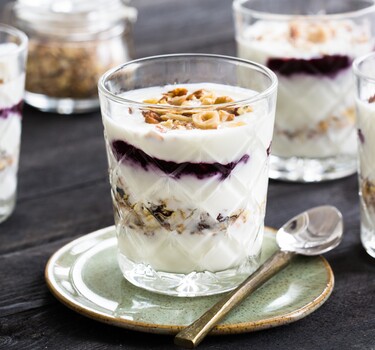 Feestelijke ontbijttrifle met laagjes jam, knapperige noten, voedzame muesli en yoghurt (of kwark). 