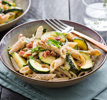 Magere penne carbonara met yoghurt, spekjes, courgette, Parmezaan en citroenrasp