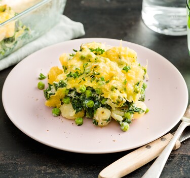 Romige gnocchi met doperwten, spinazie en graskaas uit de oven