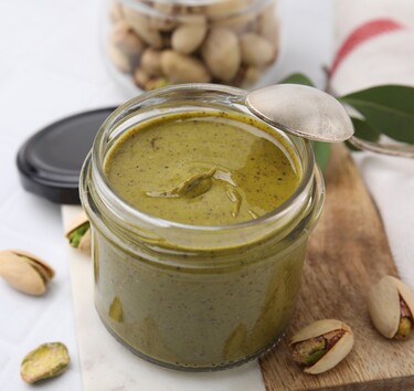 Pistachecrème in een potje met pistachenootjes eromheen.