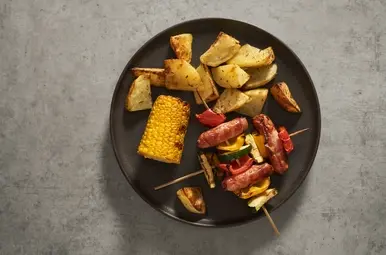 Maïskolf van de grill met worstspiesjes