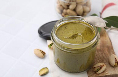 Pistachecrème in een potje met pistachenootjes eromheen.