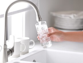 Een kraan die een glas vult met water.