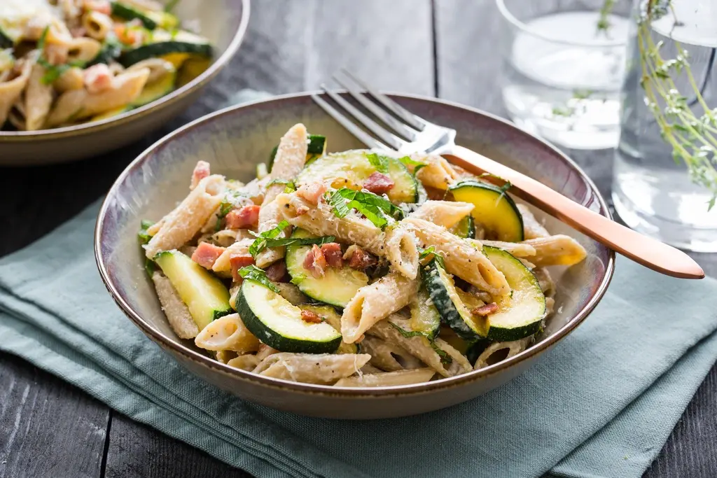 Magere penne carbonara met yoghurt, spekjes, courgette, Parmezaan en citroenrasp