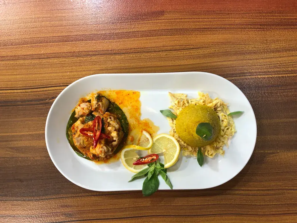 Ayam rica rica met nasi kuning, omelet en bananenblad